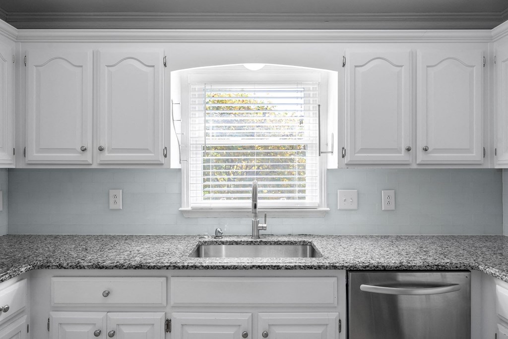 a kitchen with white cabinets and a sink and a window