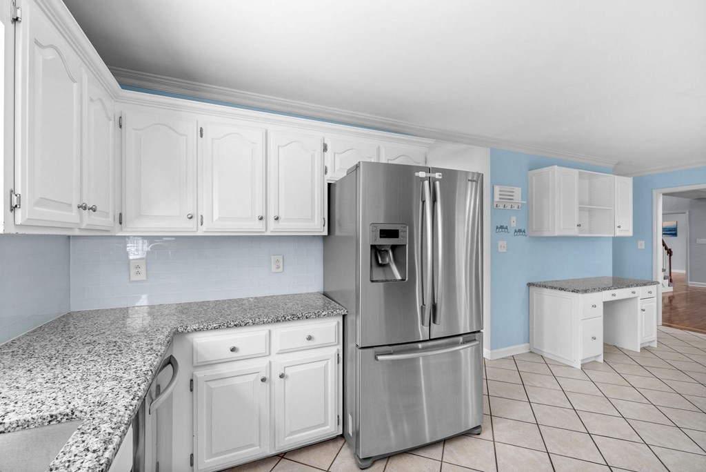 a kitchen with white cabinets and a stainless steel refrigerator