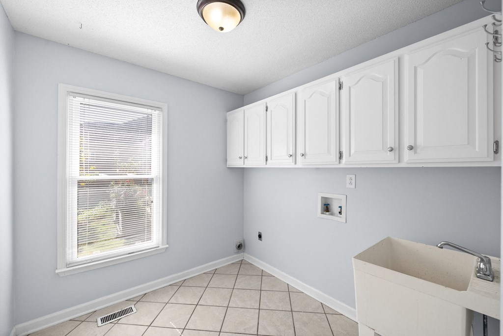 an empty kitchen with white cabinets and a window