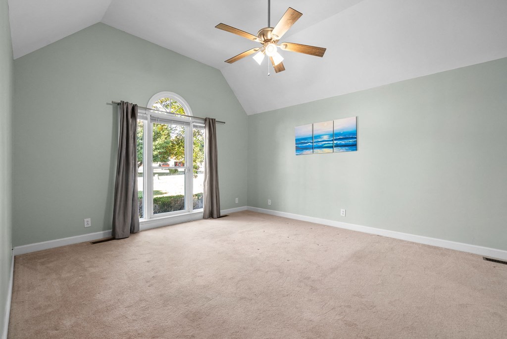 an empty living room with a ceiling fan and a window