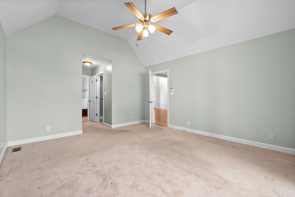 a empty living room with green walls and a ceiling fan
