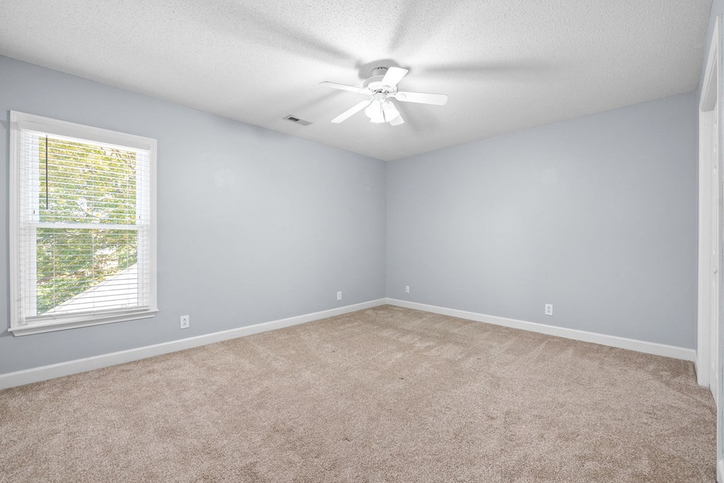 an empty room with a window and a ceiling fan