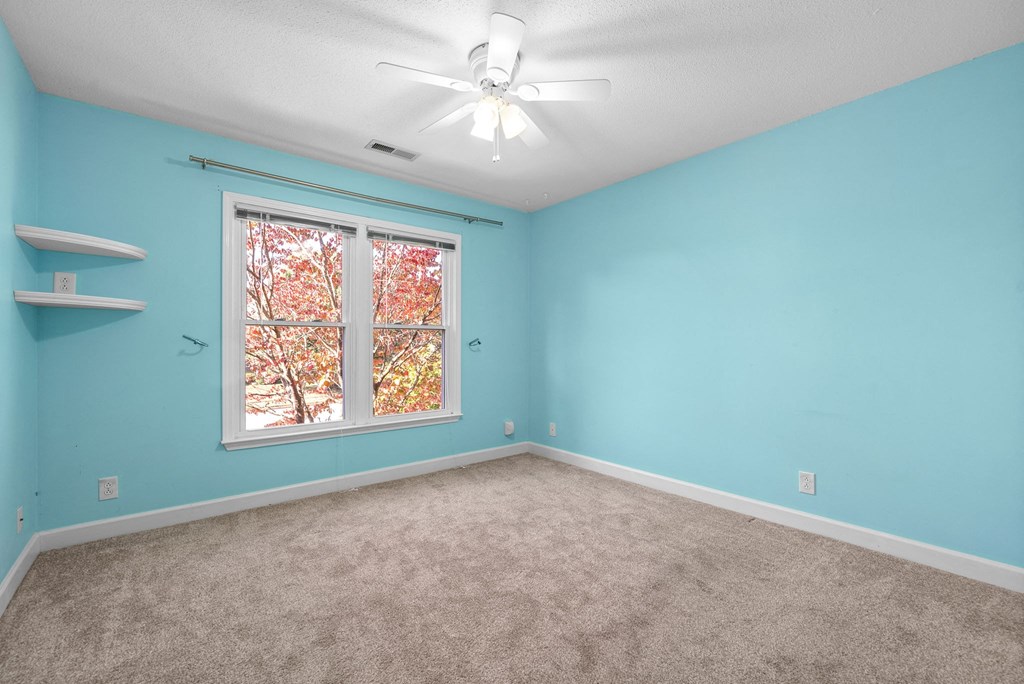 an empty bedroom with a window and a ceiling fan
