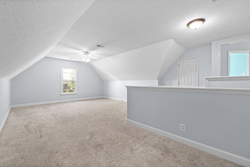 an empty attic with a door and a ceiling fan