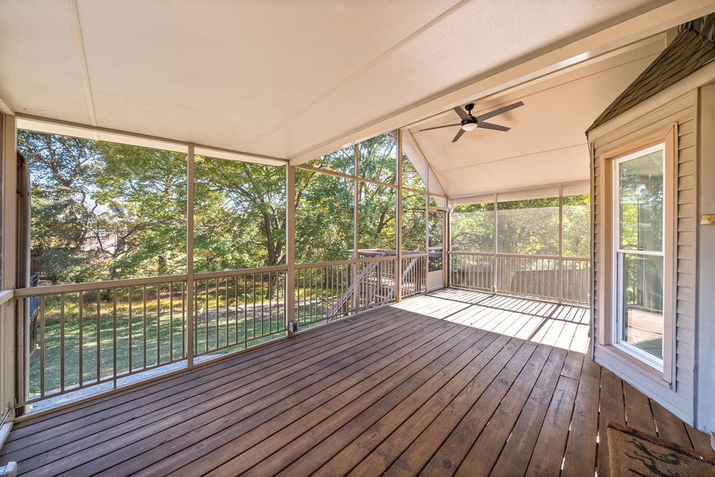 the deck of a house has a wood floor and a ceiling fan