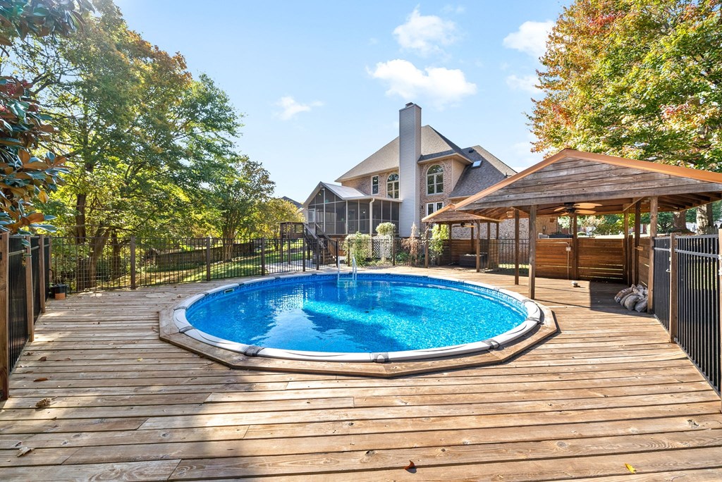 a backyard pool with a pavilion and a house