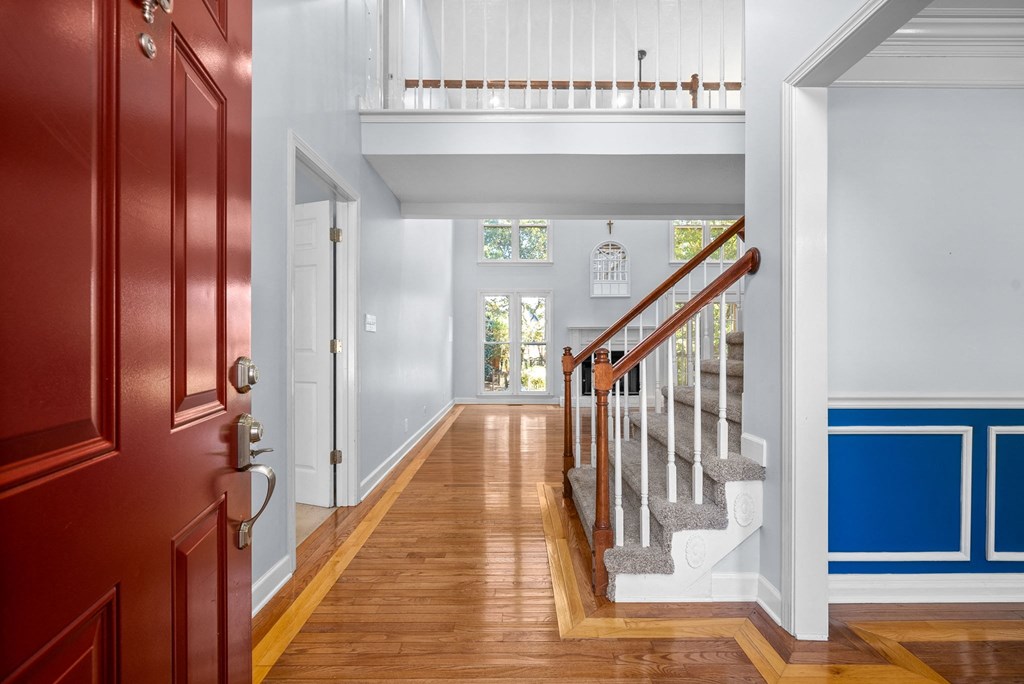 a hallway with a red door and a staircase with a blue wall and wood floors