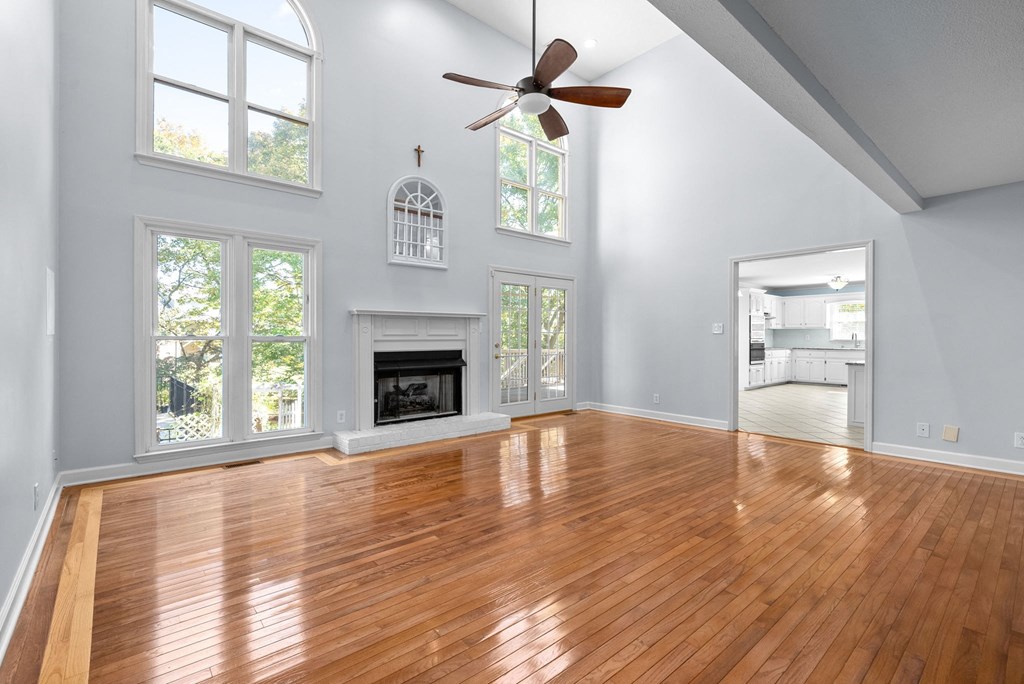 an empty living room with a fireplace and a ceiling fan