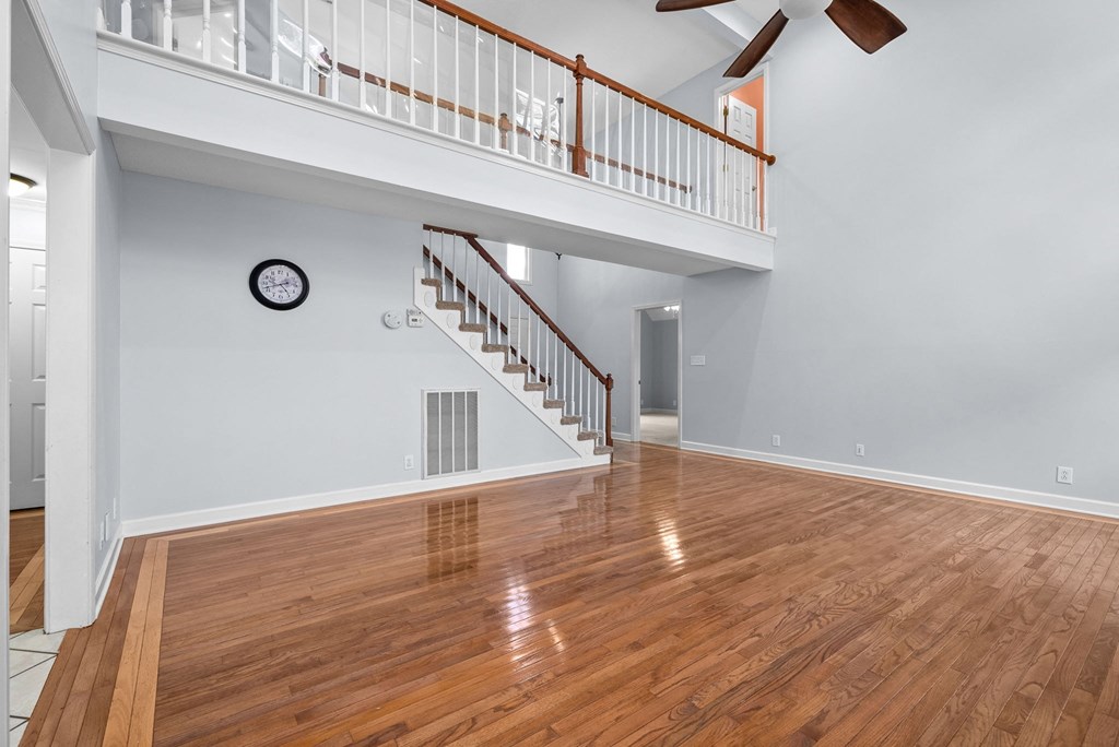 a living room with a staircase and a clock on the wall