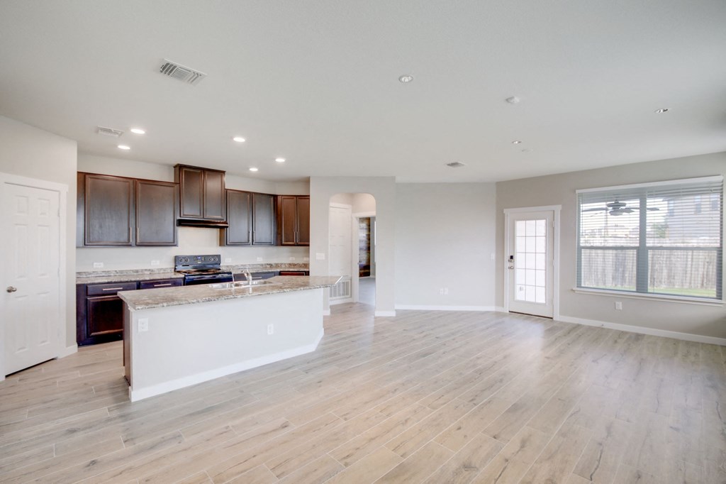 an open kitchen and living room with wood flooring and a large window