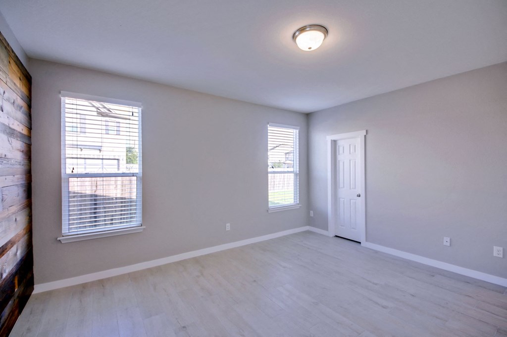 the spacious living room of an empty home with white walls and wood flooring