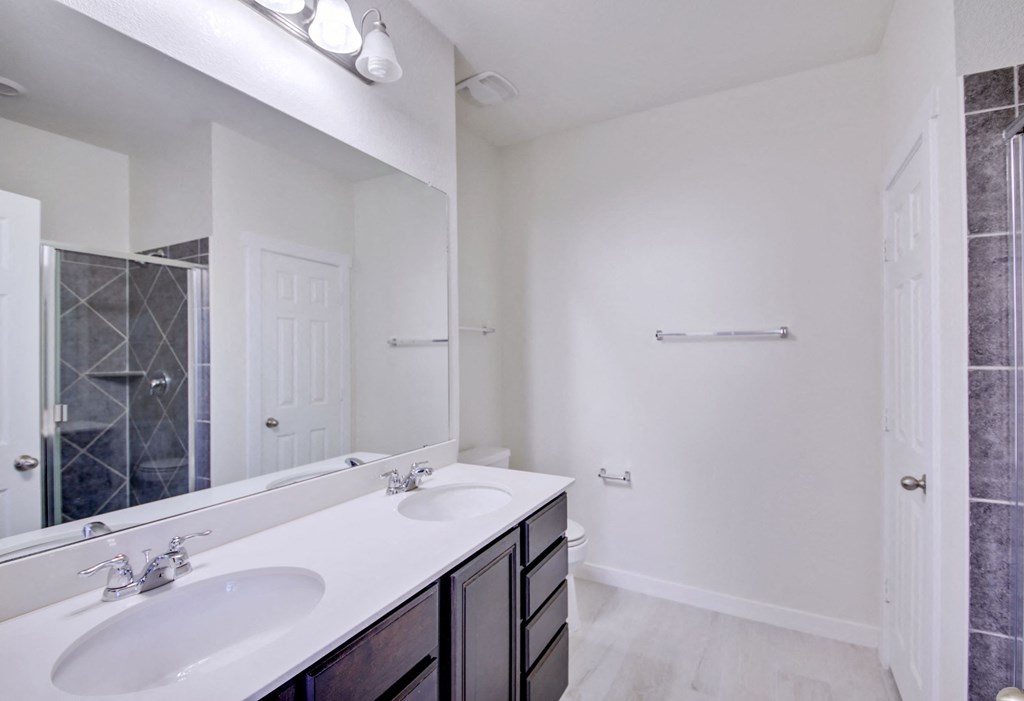 an empty bathroom with two sinks and a mirror