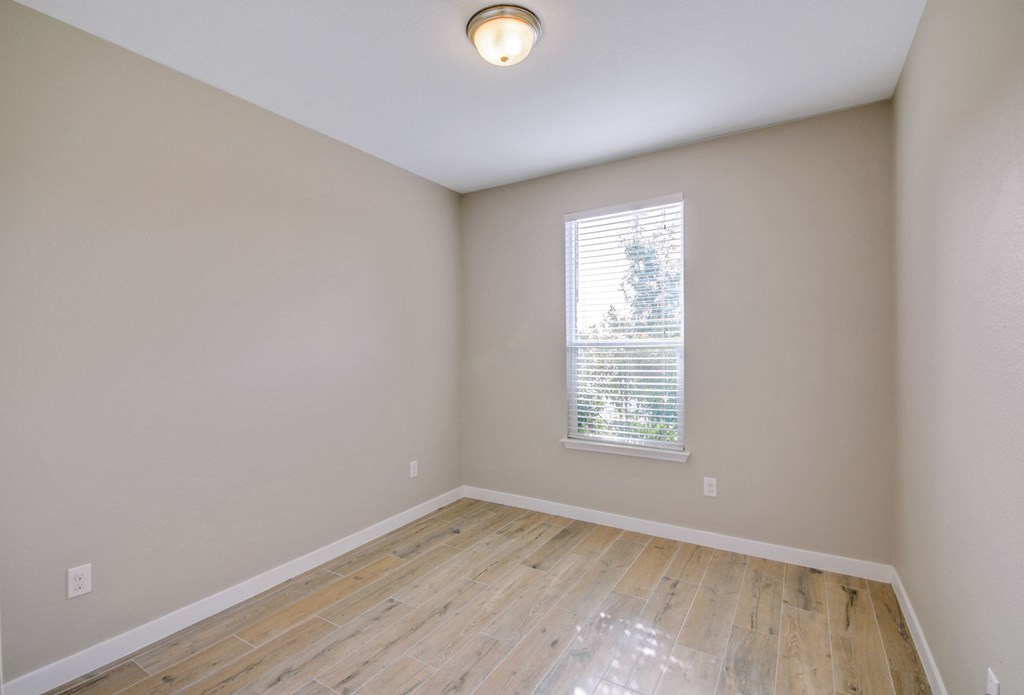 an empty room with wood floors and a window