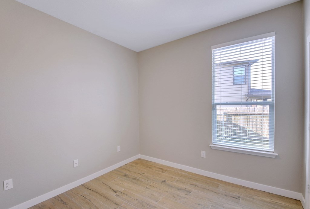 an empty room with wood floors and a window