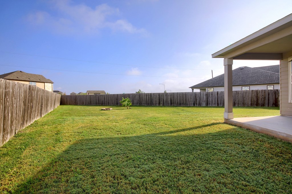 the backyard of a house with a lawn and a fence