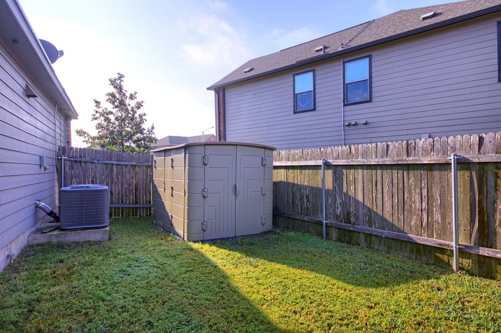 a backyard with a chicken coop and a fence and a house