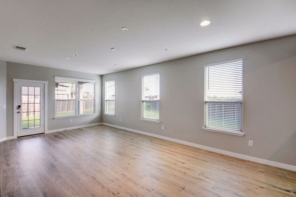 the living room of an empty house with wood floors and windows