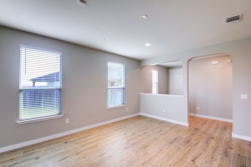 an empty living room with a hard wood floor and windows