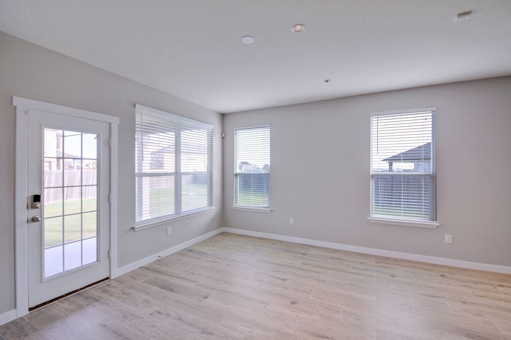 the living room of an empty house with a door and windows