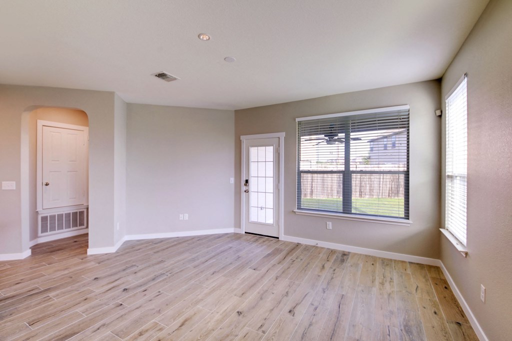 an empty living room with wood floors and a window