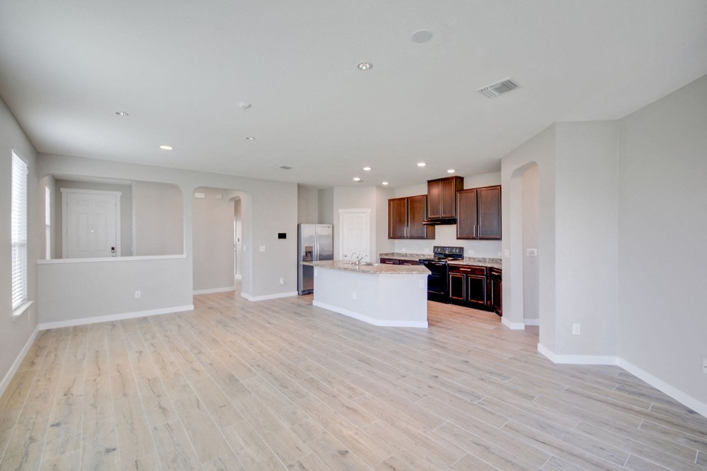 an empty living room and kitchen with white walls and wood flooring