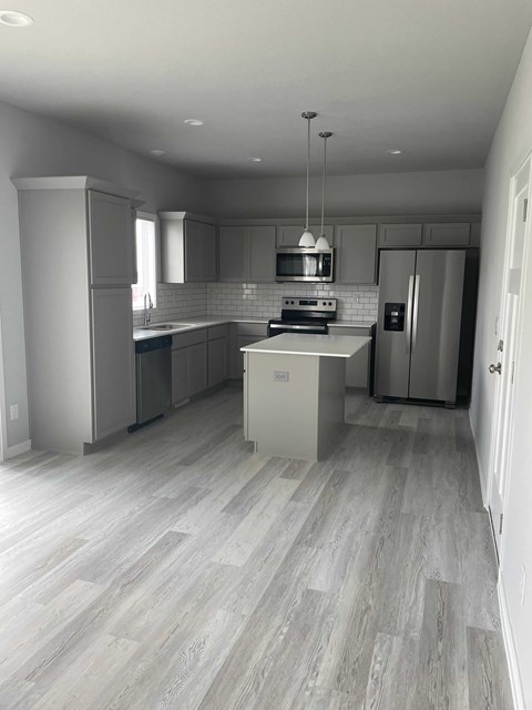 A modern kitchen with a refrigerator, stove, and cabinets.