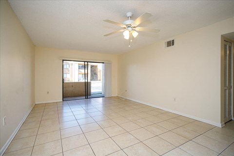 A spacious room with a ceiling fan and tiled flooring.