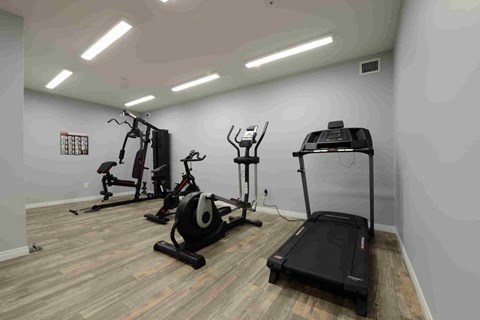 A gym with a treadmill, elliptical trainer, and stationary bike.