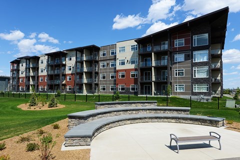 A modern apartment complex with a circular patio and bench.