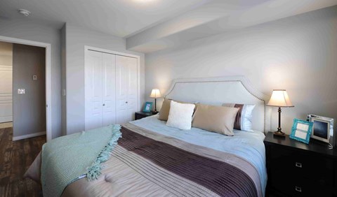 A bedroom with a large bed and a nightstand with a lamp.