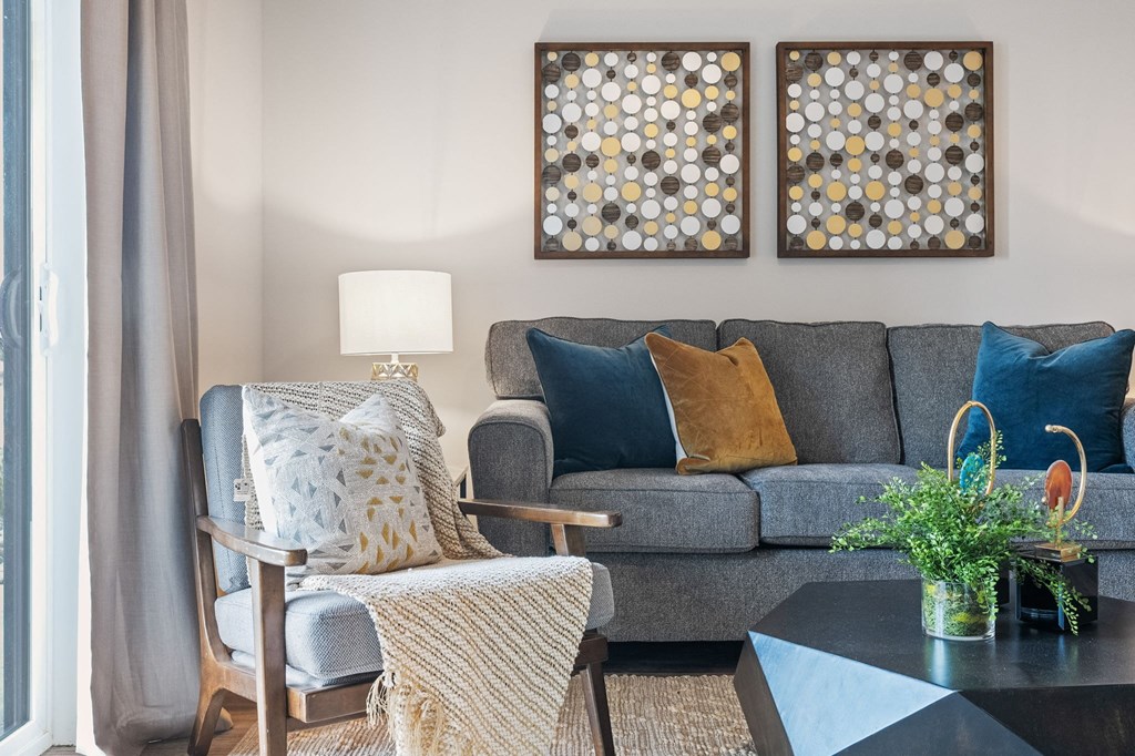 a living room with a gray couch and two paintings on the wall