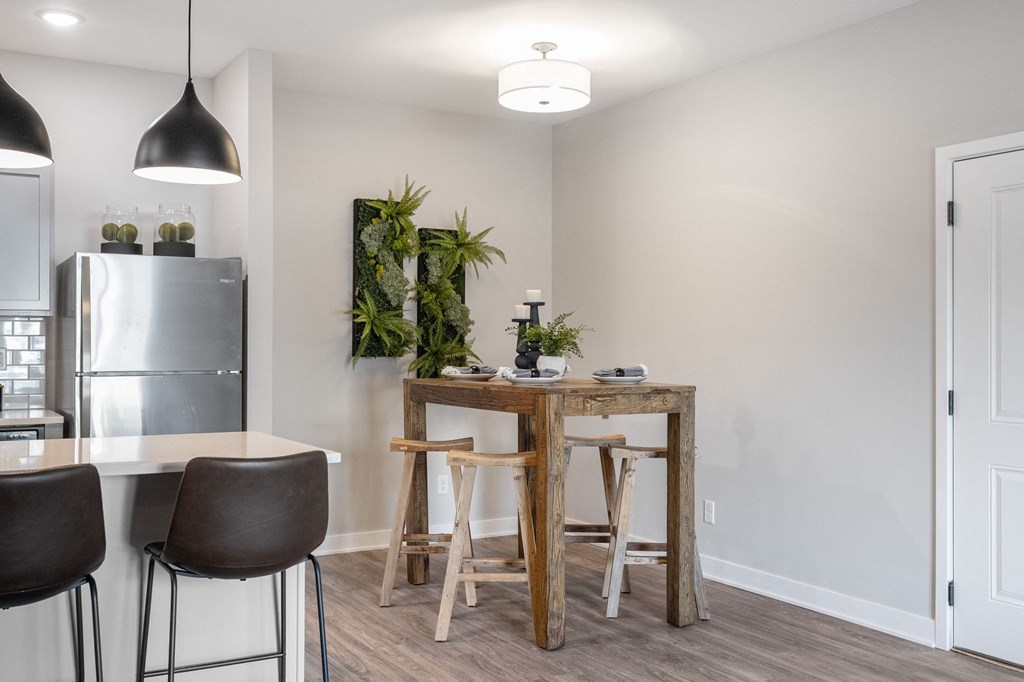 a dining area with a table and chairs and a kitchen with a refrigerator