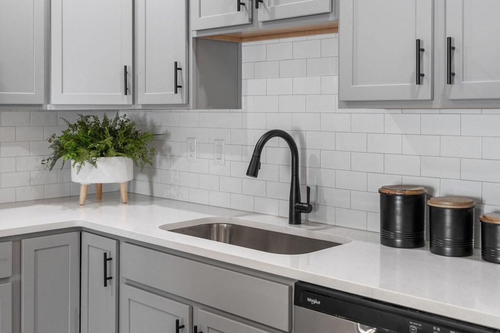 a kitchen with white cabinets and a sink and a black faucet