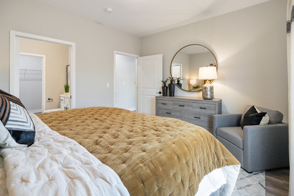 a bedroom with a bed and a chair and a mirror