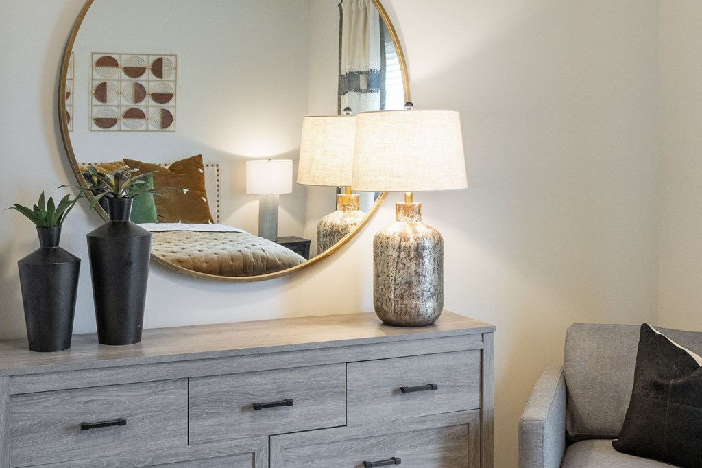 a bedroom with a dresser with a lamp and a mirror