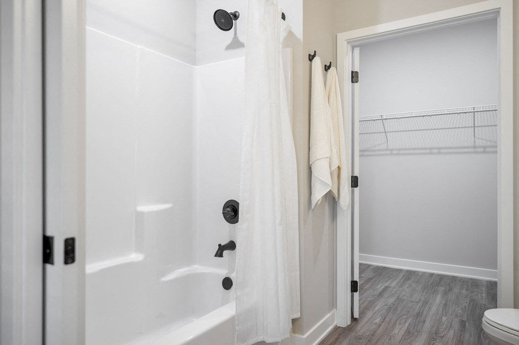 a bathroom with a shower and a toilet and a white shower curtain