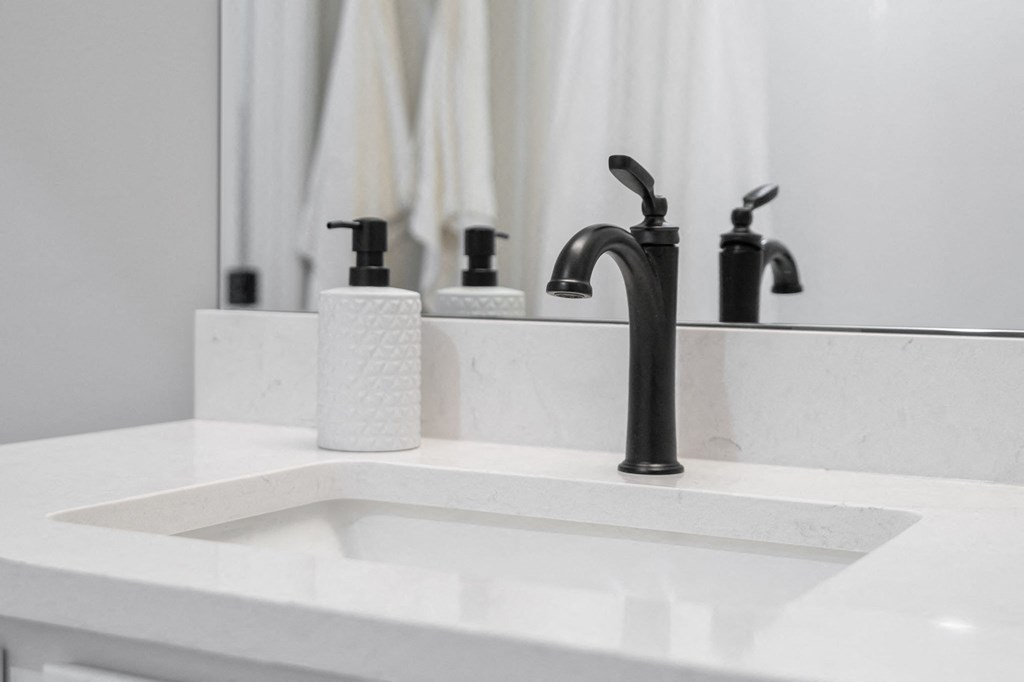 a white sink with a black faucet in a bathroom