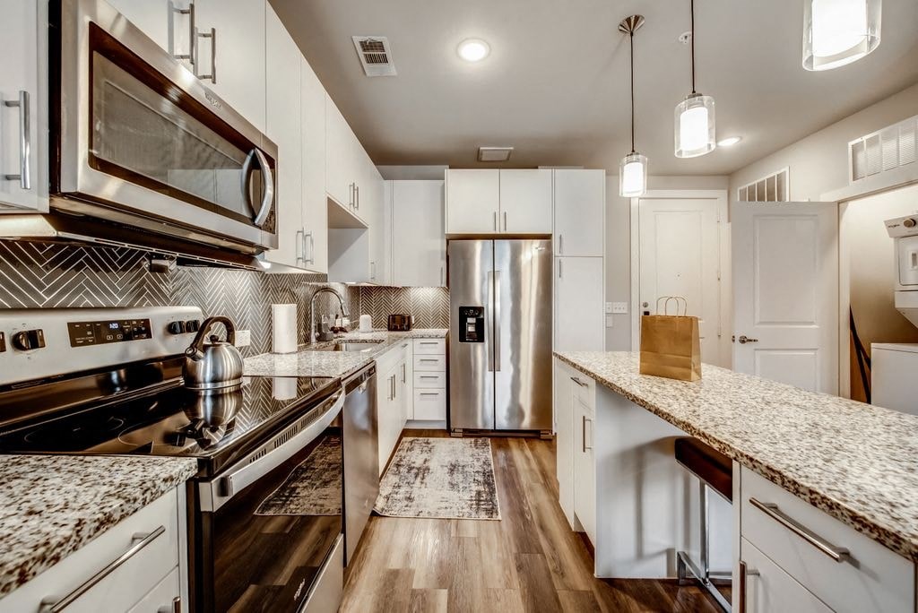 a kitchen with marble counter tops and a stainless steel refrigerator