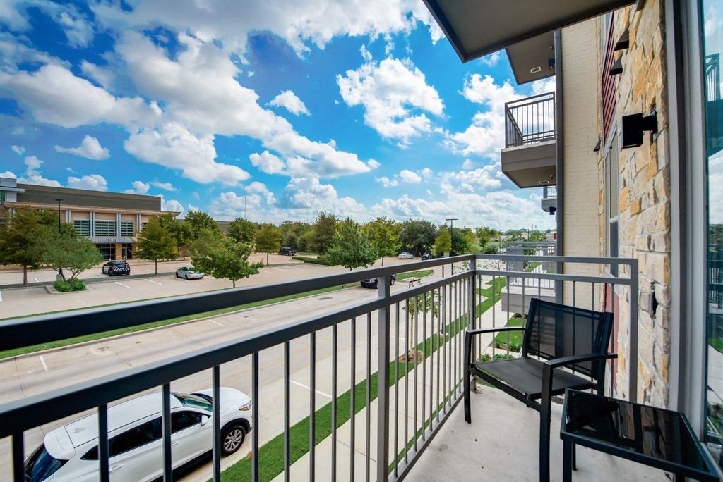 a balcony with a chair and a view of a parking lot