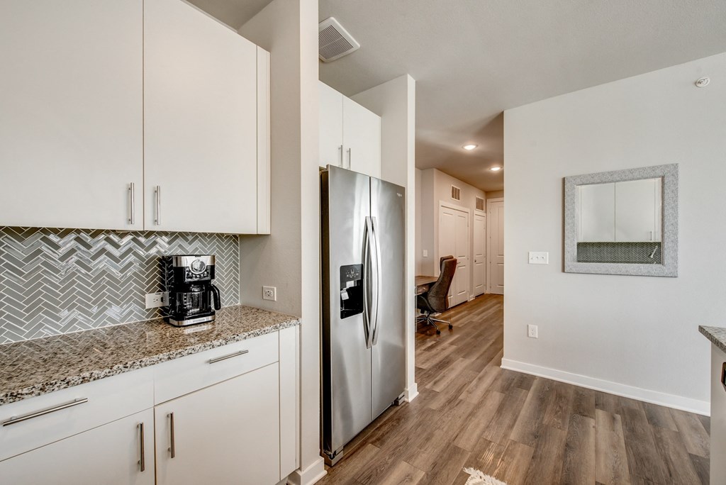 a kitchen with white cabinets and a stainless steel refrigerator