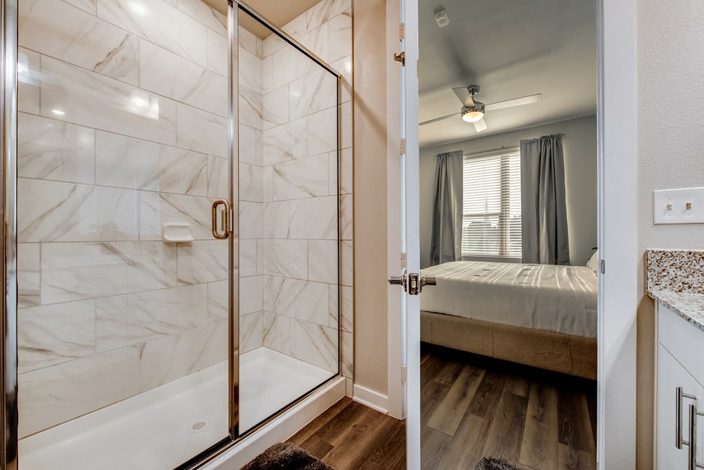 a bathroom with a shower and a bedroom with a bed