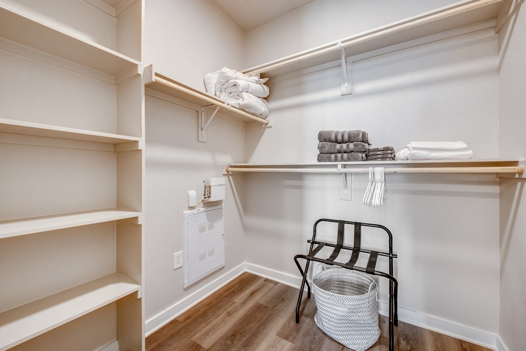 a walk in closet with a chair and shelves