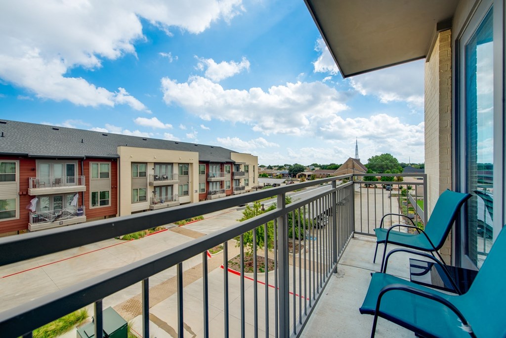 the view from the balcony of an apartment building with blue chairs