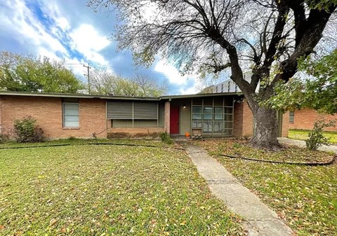 A house with a red door and a tree in front.