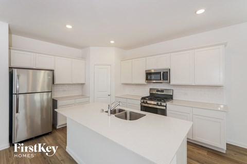 a white kitchen with stainless steel appliances and white counter tops