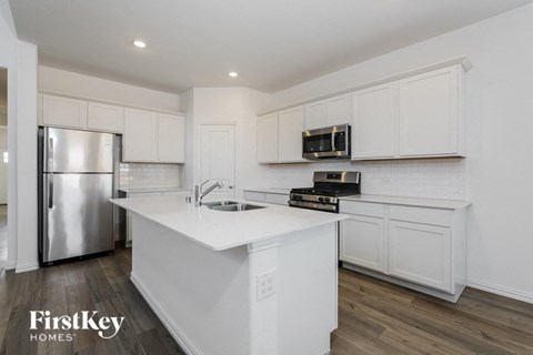 A kitchen with white cabinets and a stainless steel refrigerator.