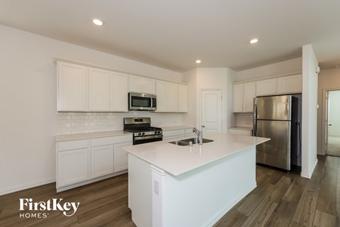 A kitchen with white cabinets and a stainless steel refrigerator.
