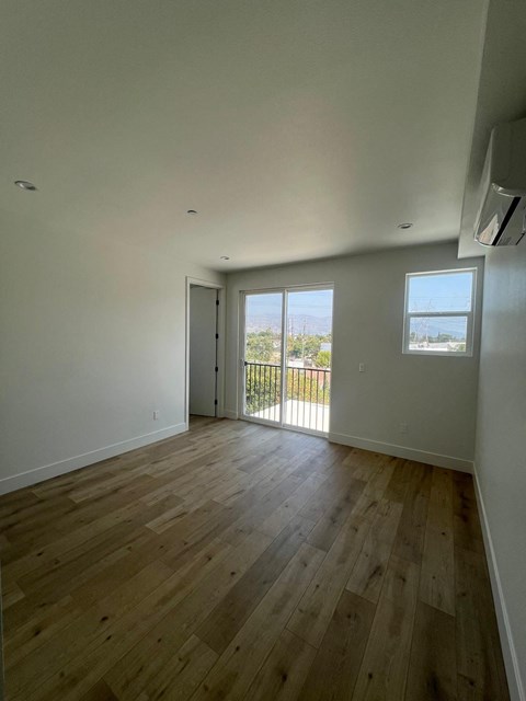 an empty living room with wooden floors and a balcony