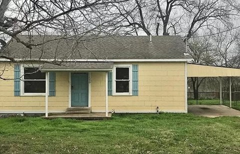 a yellow house with a blue door in a field