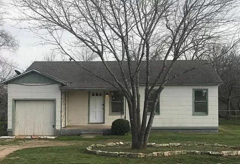 a small white house with a tree in the front